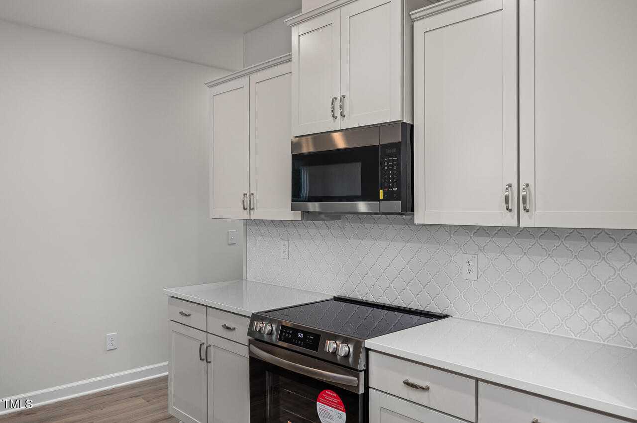 Modern white kitchen with shaker cabinets, stainless steel range and microwave, subway tile backsplash in Davidson Homes Adalynn B, Lillington NC