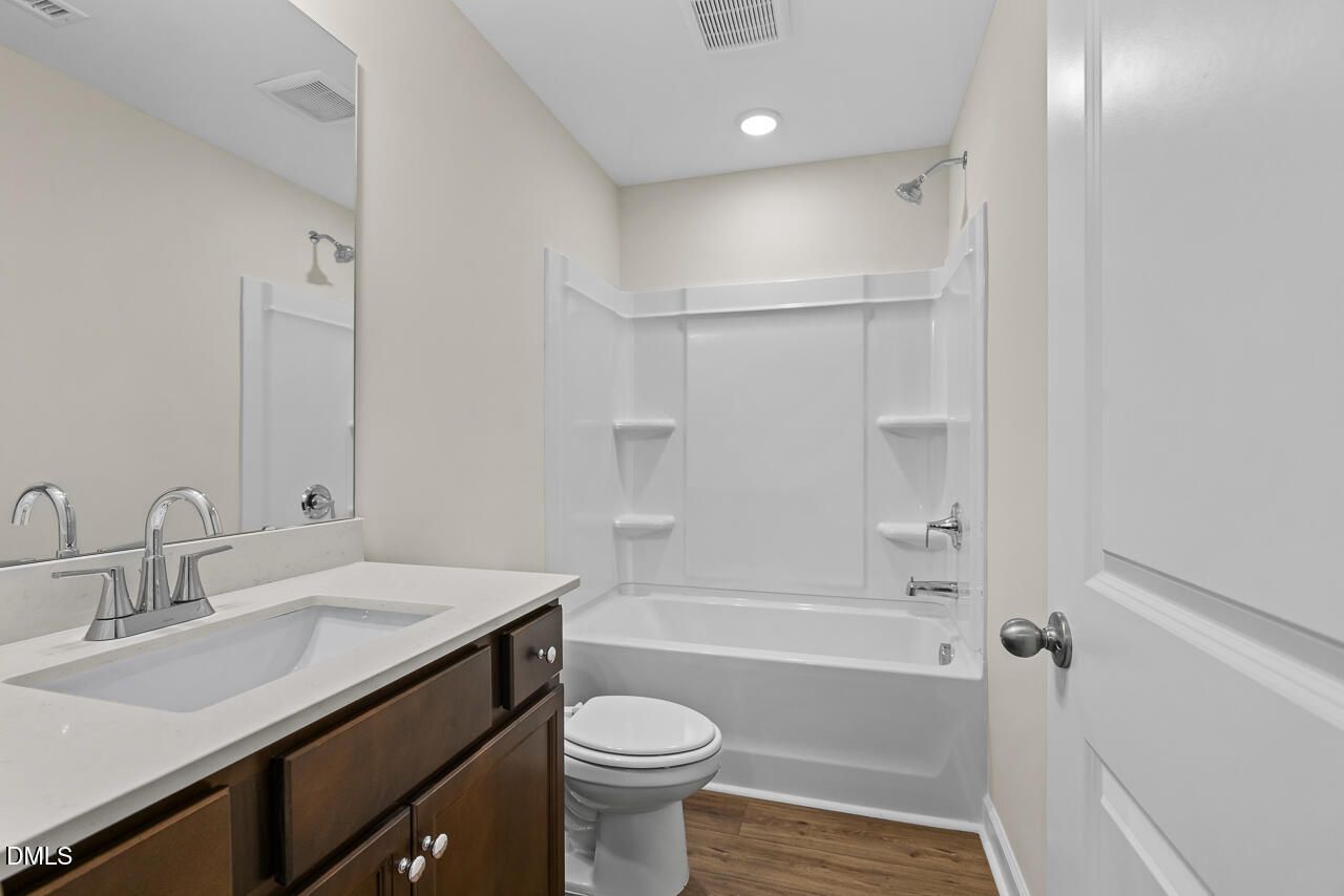 Full bathroom with white tub-shower combo, dark wood vanity, and quartz countertop in Davidson Homes' Birch II C, Wake Forest, NC