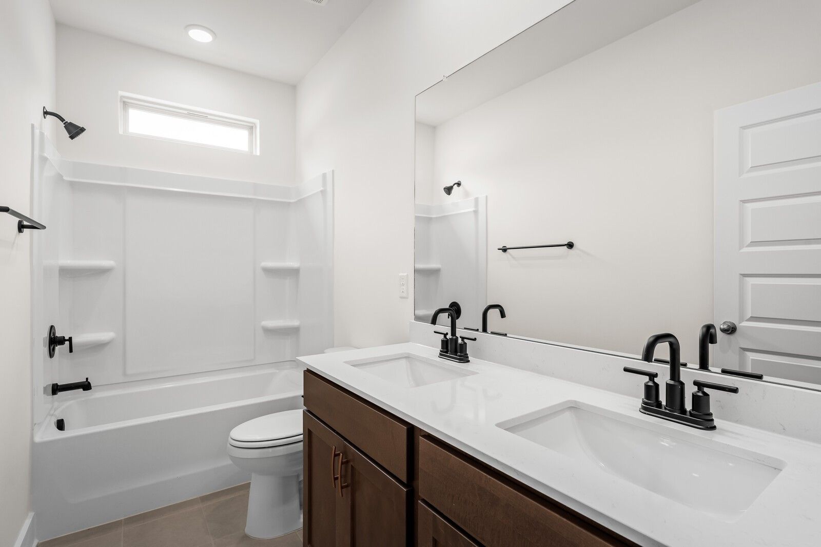 Modern bathroom with double vanity, dark wood cabinets, and tub-shower combo in Woods Crossing, Gallatin, Tennessee.