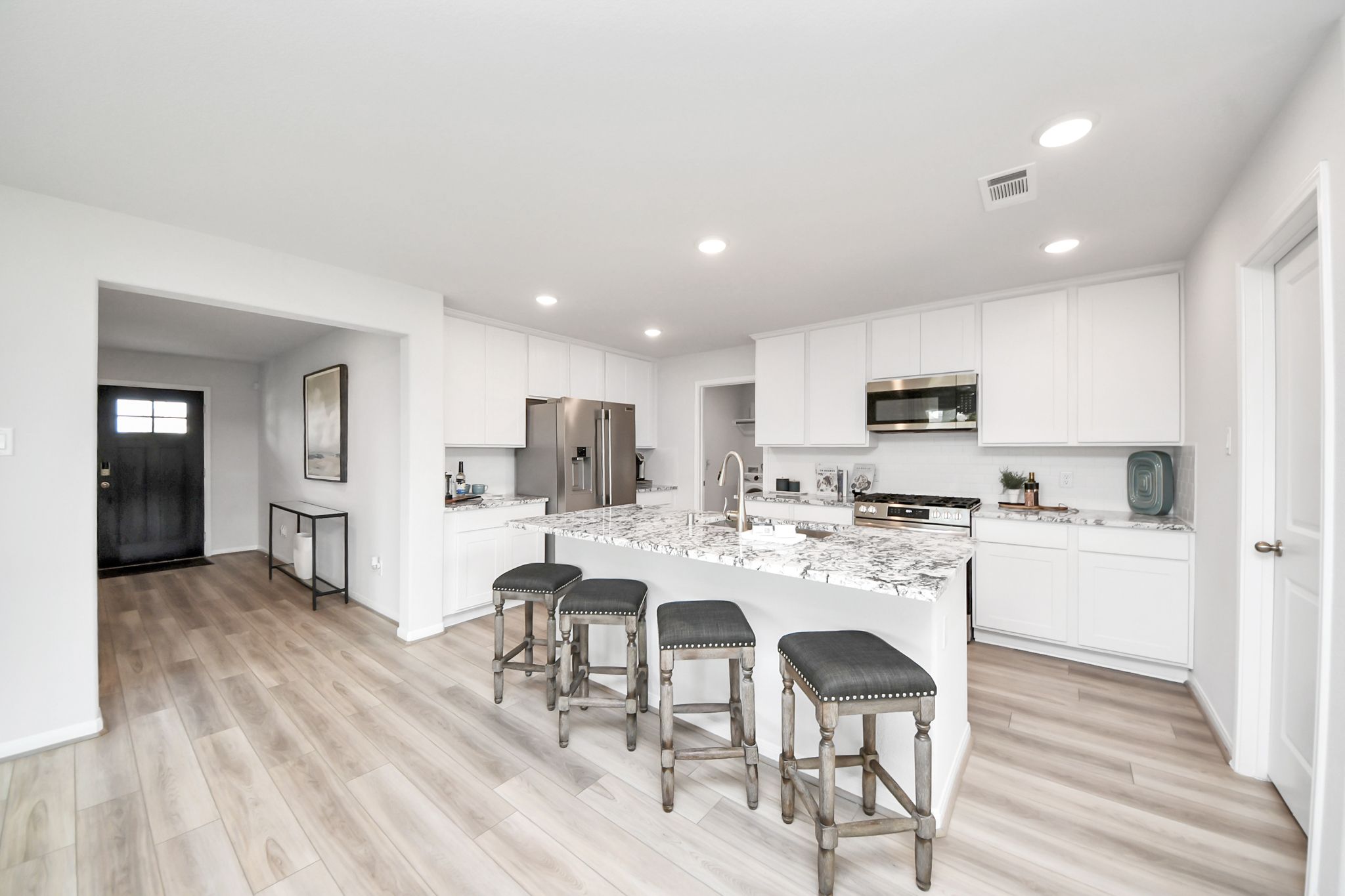 Modern kitchen with white cabinets and granite island seating at Sunterra in Katy, Texas by Davidson Homes
