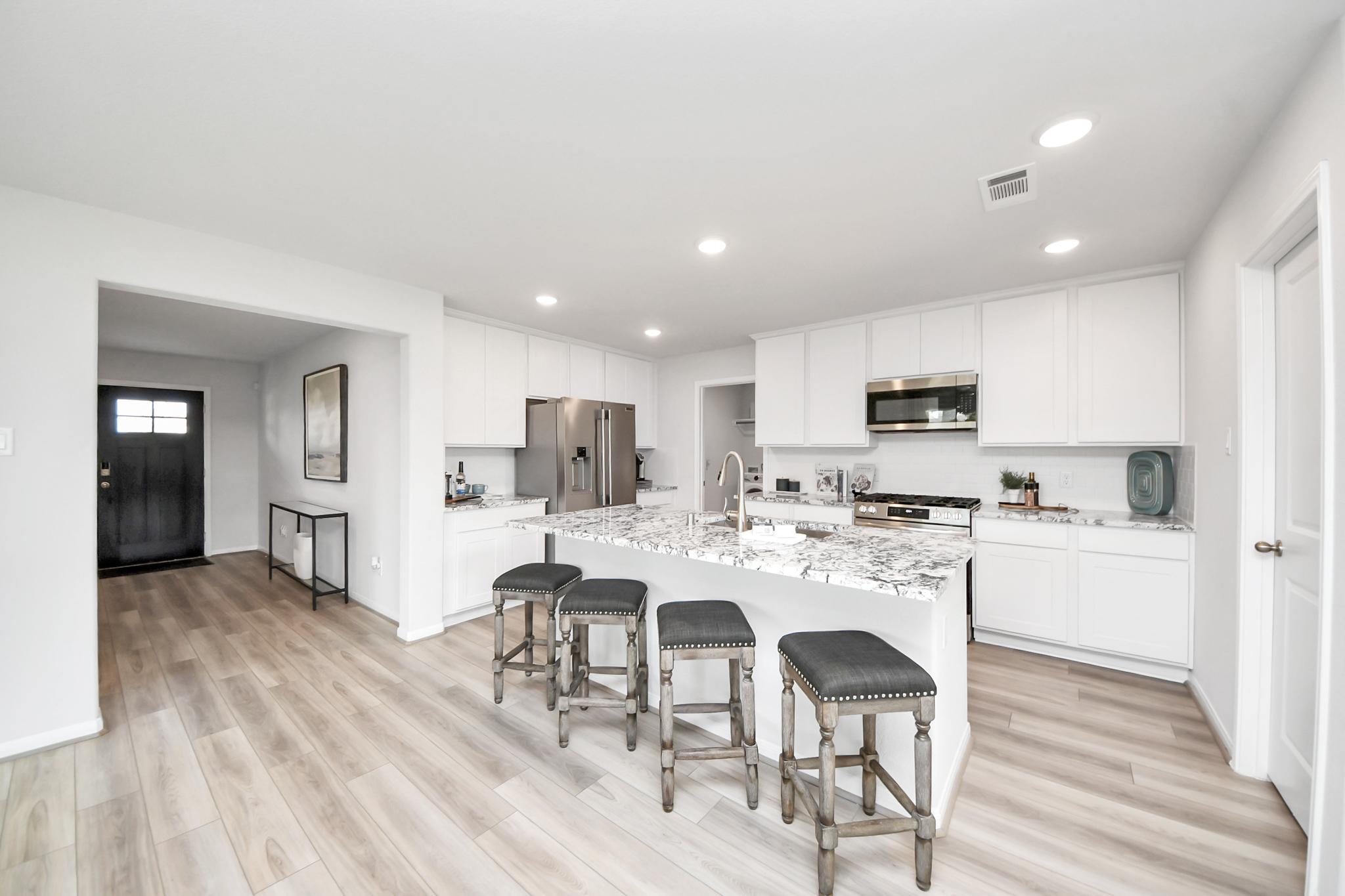 Modern kitchen with white cabinets and granite island seating at Sunterra in Katy, Texas by Davidson Homes