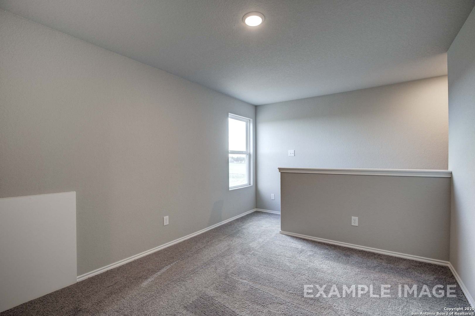 Bright upstairs loft with gray walls, carpeted floor, window, and balcony railing in Davidson Homes The Blanco C, Agave San Antonio