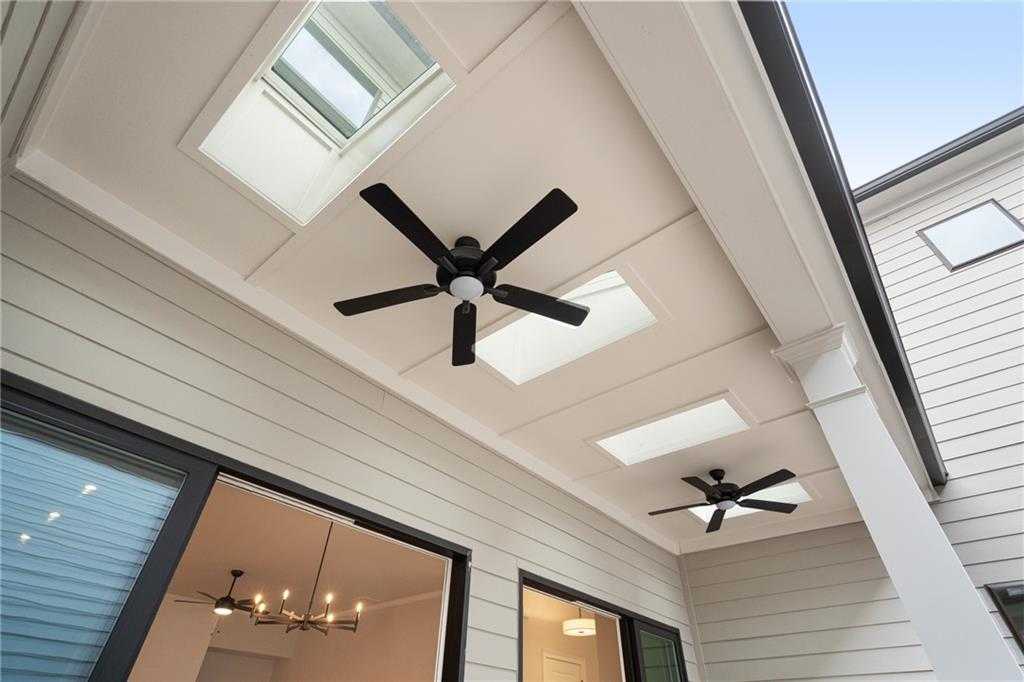 Covered patio with skylights, black ceiling fans, and chandelier in Davidson Homes The Seaside B, Woodstock, GA