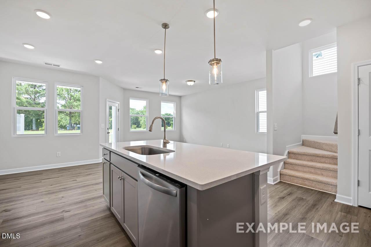 Modern kitchen island with quartz countertops and pendant lighting in The Graham floor plan at Springvale, Fuquay-Varina.