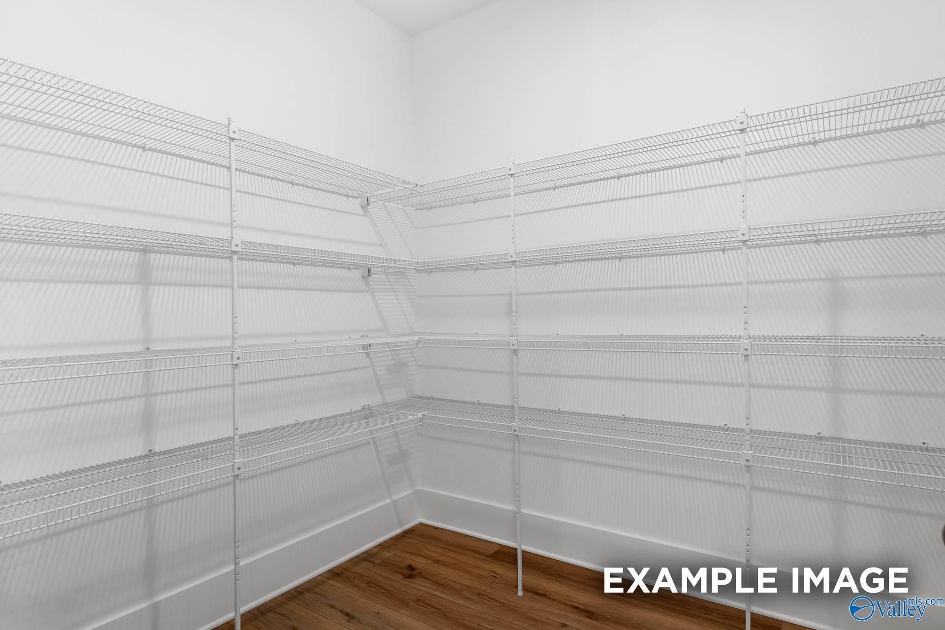 Spacious corner pantry with white wire shelving and hardwood floors in The Finleigh 5-bedroom home, Decatur, Alabama