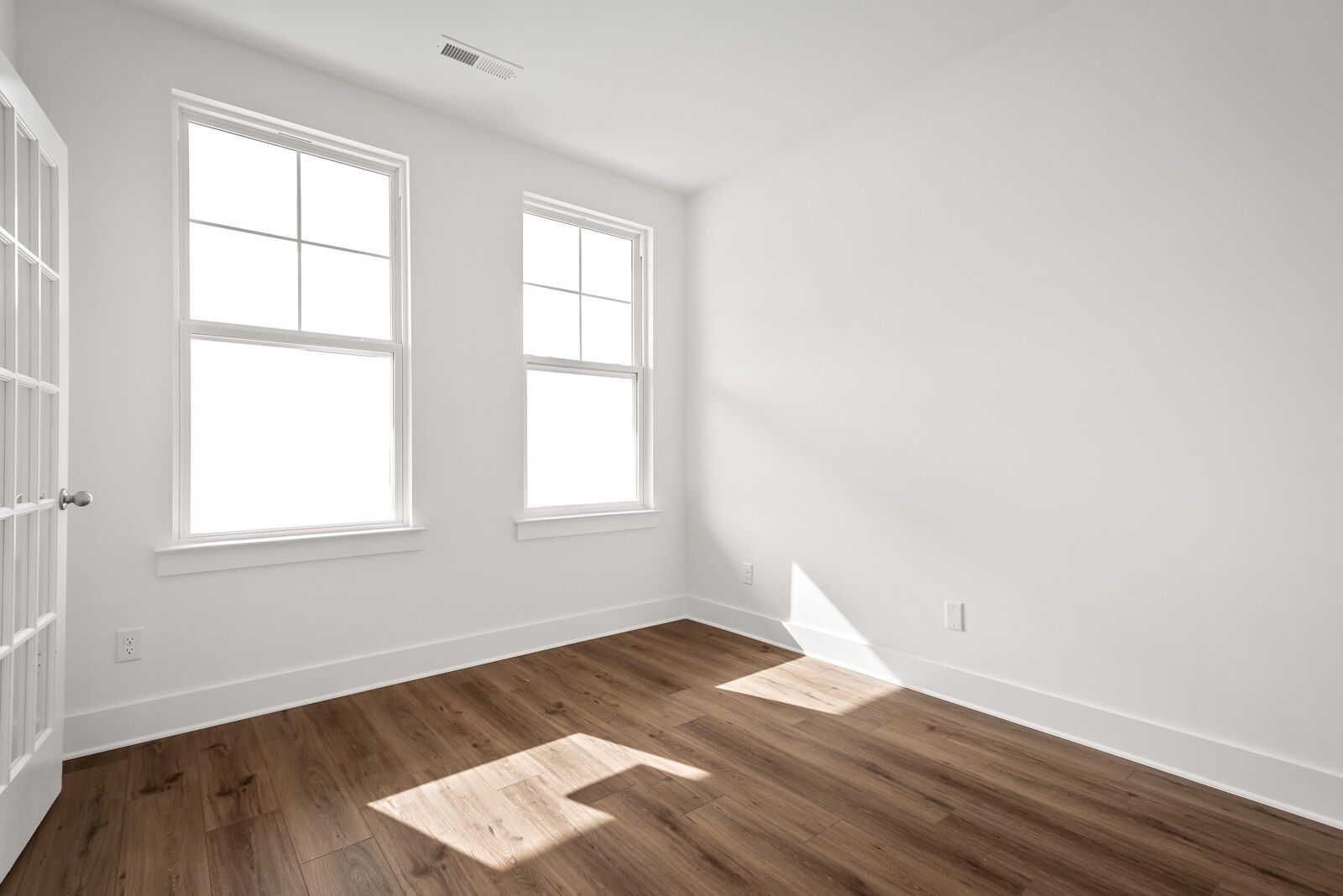 Bright secondary bedroom with hardwood floors and large windows in Davidson Homes The Logan C, Gallatin, Tennessee