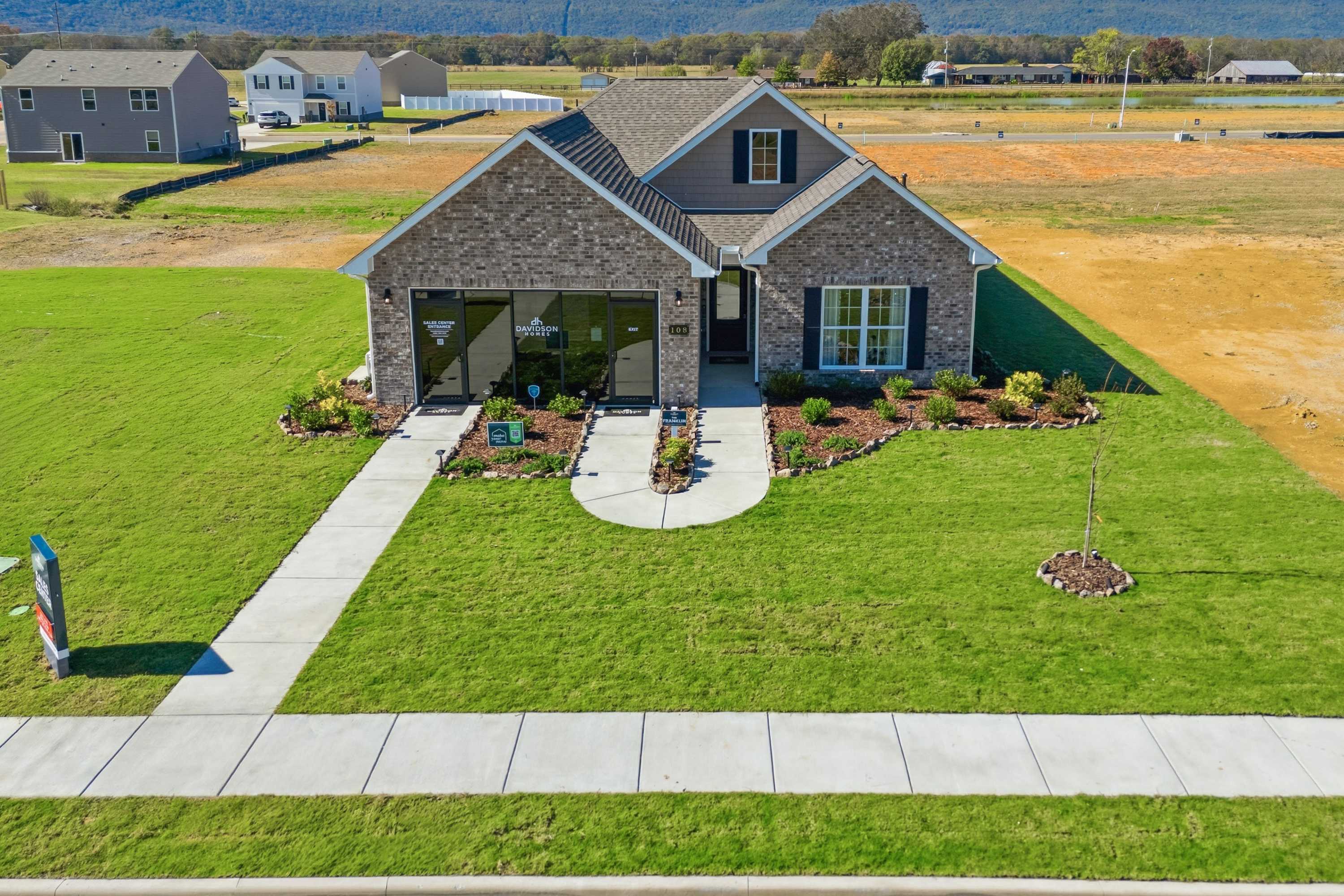 Brick Craftsman home in Ramsay Cove, Owens Cross Roads AL with blue shutters, large windows, landscaped yard and sidewalk