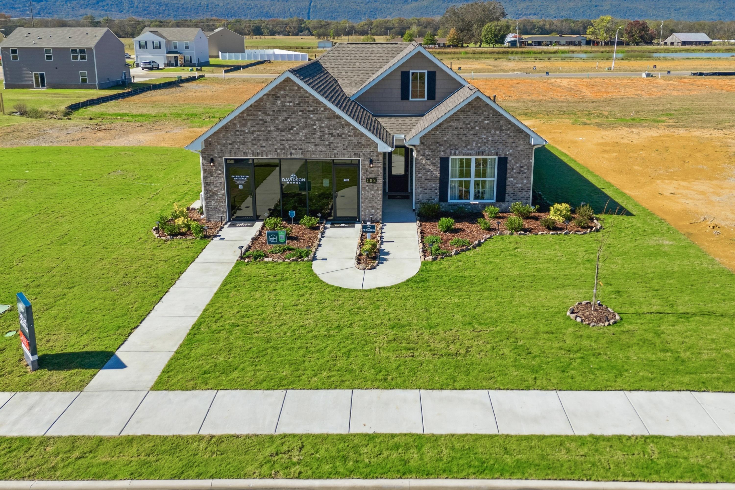 Brick Craftsman home in Ramsay Cove, Owens Cross Roads AL with blue shutters, large windows, landscaped yard and sidewalk