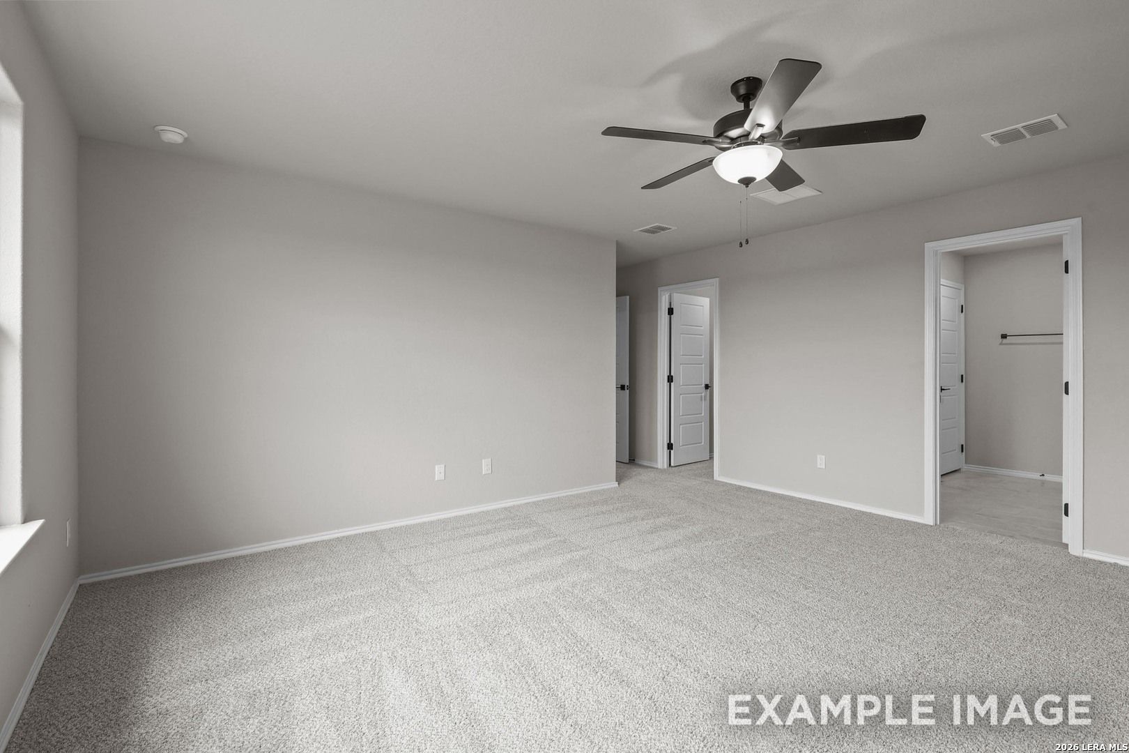 Spacious primary bedroom with ceiling fan, neutral carpet, and walk-in closet access in Davidson Homes The Murray H, Converse, TX