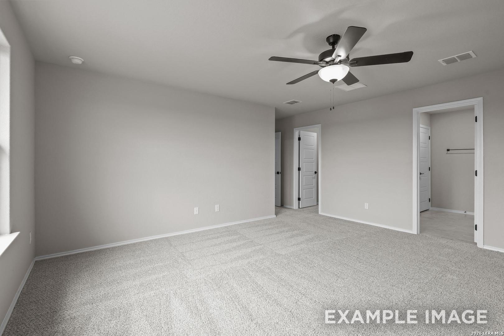 Spacious primary bedroom with ceiling fan, neutral carpet, and walk-in closet access in Davidson Homes The Murray H, Converse, TX