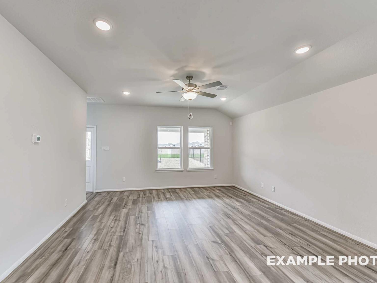 Spacious living room with wood-look flooring and vaulted ceilings in The Laguna C floor plan at River Ranch Meadows.