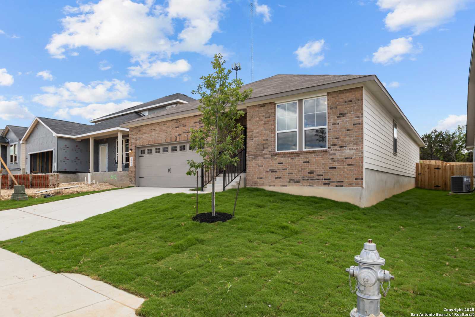 Modern 1-story brick home with 2-car garage, driveway, and lush lawn in Royal Crest, San Antonio - Davidson Homes The Daphne G