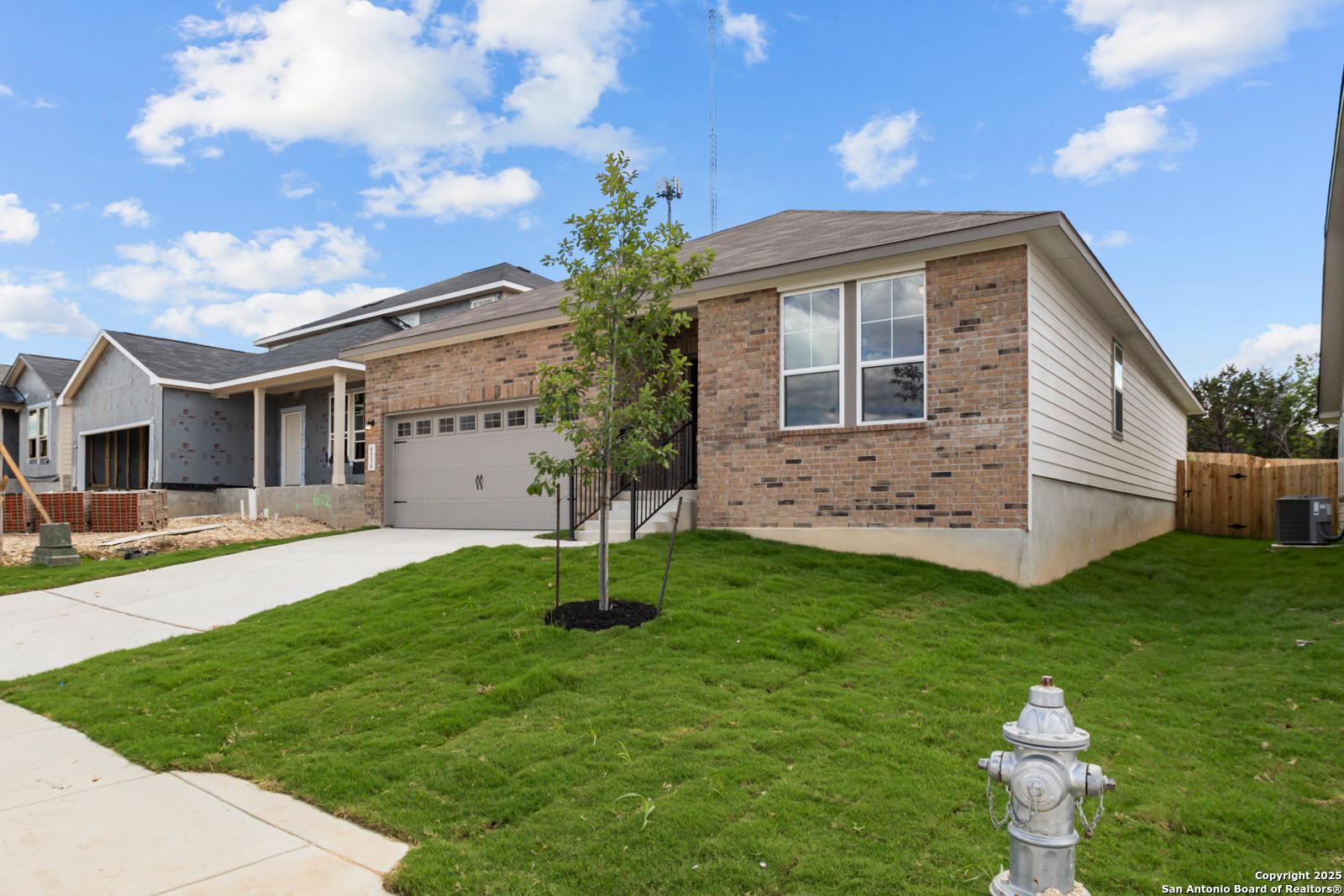 Modern 1-story brick home with 2-car garage, driveway, and lush lawn in Royal Crest, San Antonio - Davidson Homes The Daphne G
