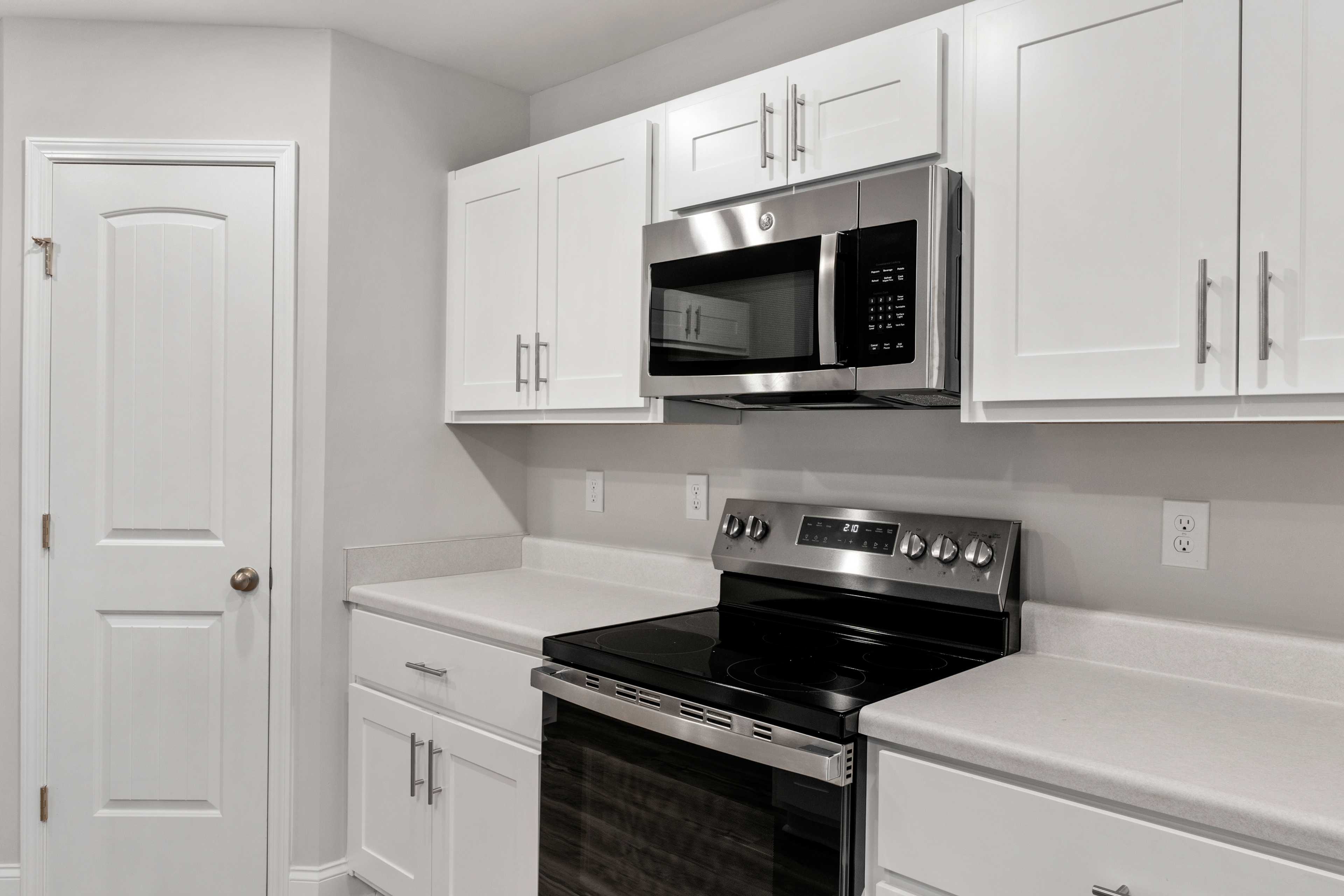 Spacious kitchen in Collins Lane, Meridianville AL with white shaker cabinets, stainless steel microwave, range and quartz counters