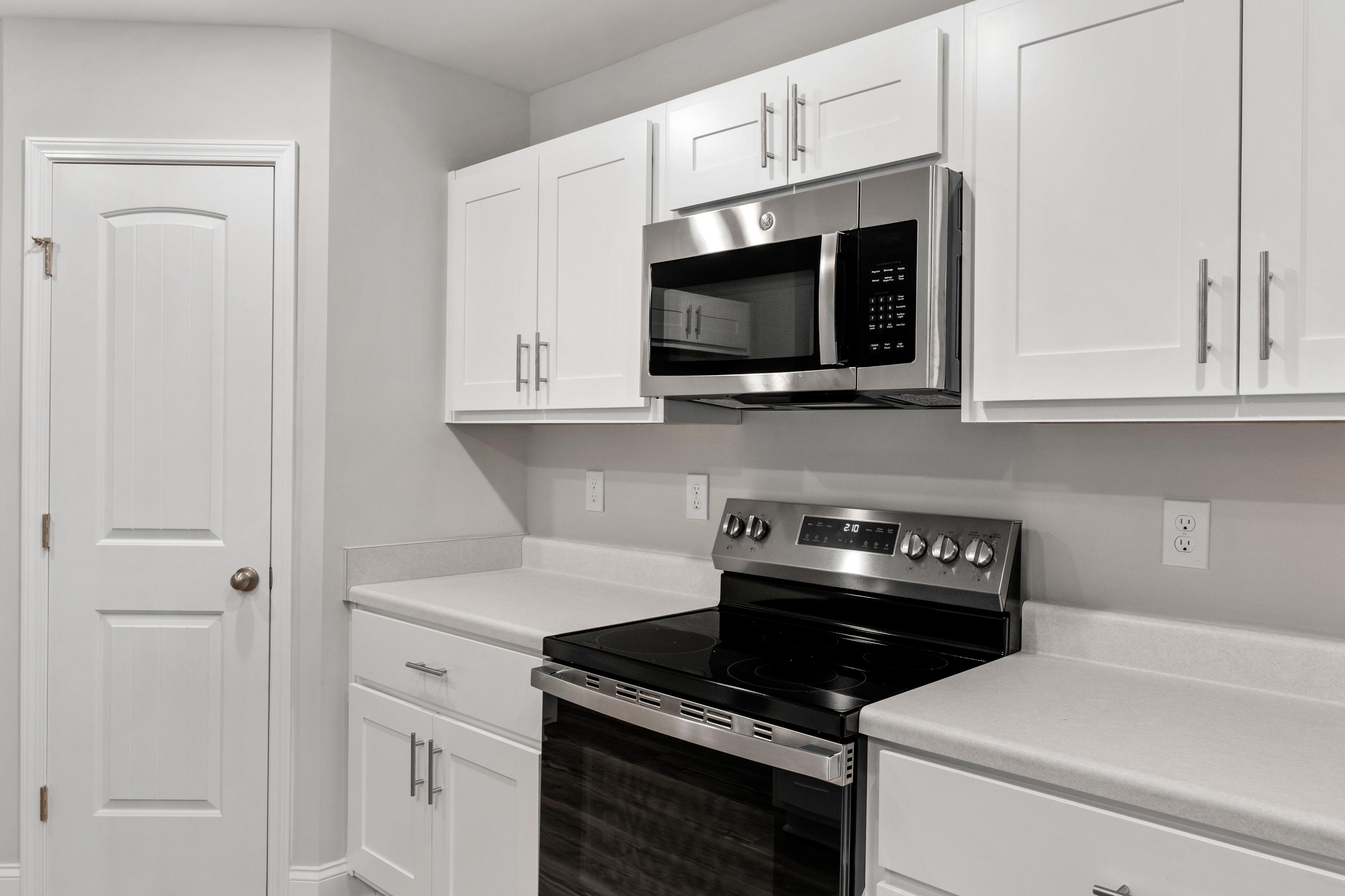 Spacious kitchen in Collins Lane, Meridianville AL with white shaker cabinets, stainless steel microwave, range and quartz counters