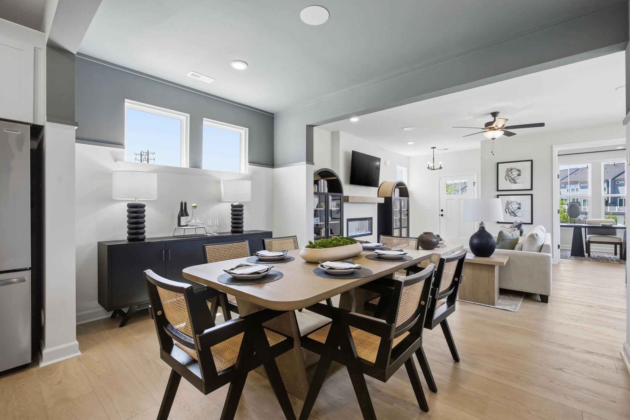 Spacious open-concept dining area at Forestville Yard in Knightdale NC with wooden table, rattan chairs, set plates, adjacent kitchen and living room
