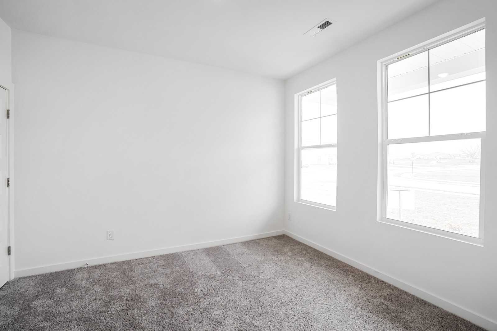 Bright secondary bedroom with large windows, white walls, and gray carpet in Davidson Homes The Logan B, Calista Farms, White House, TN