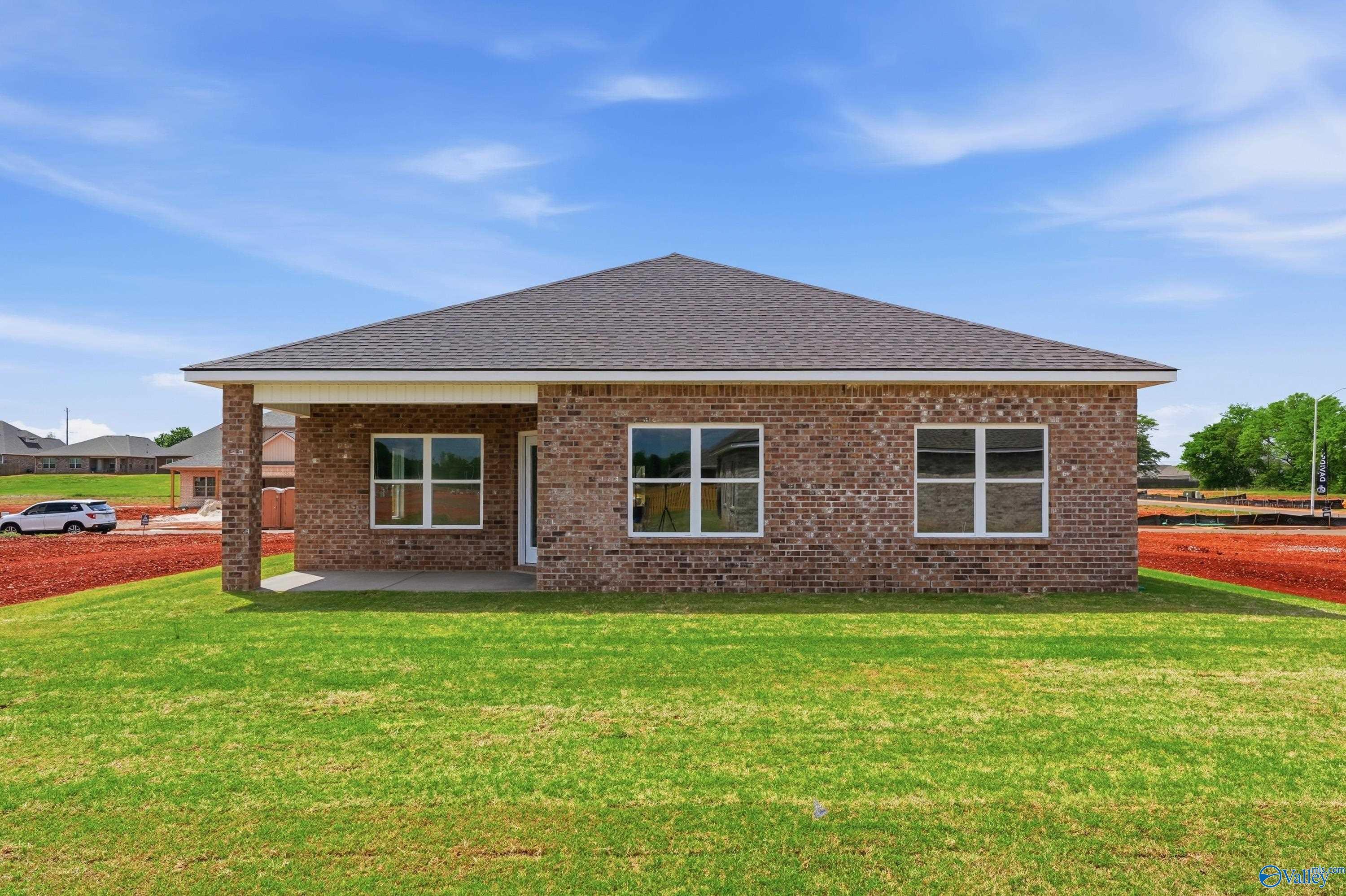 Single-story brick home with covered front porch, large windows, and gabled roof on green lawn in Lynn Meadows, Meridianville, Alabama - Davidson Homes The Franklin C