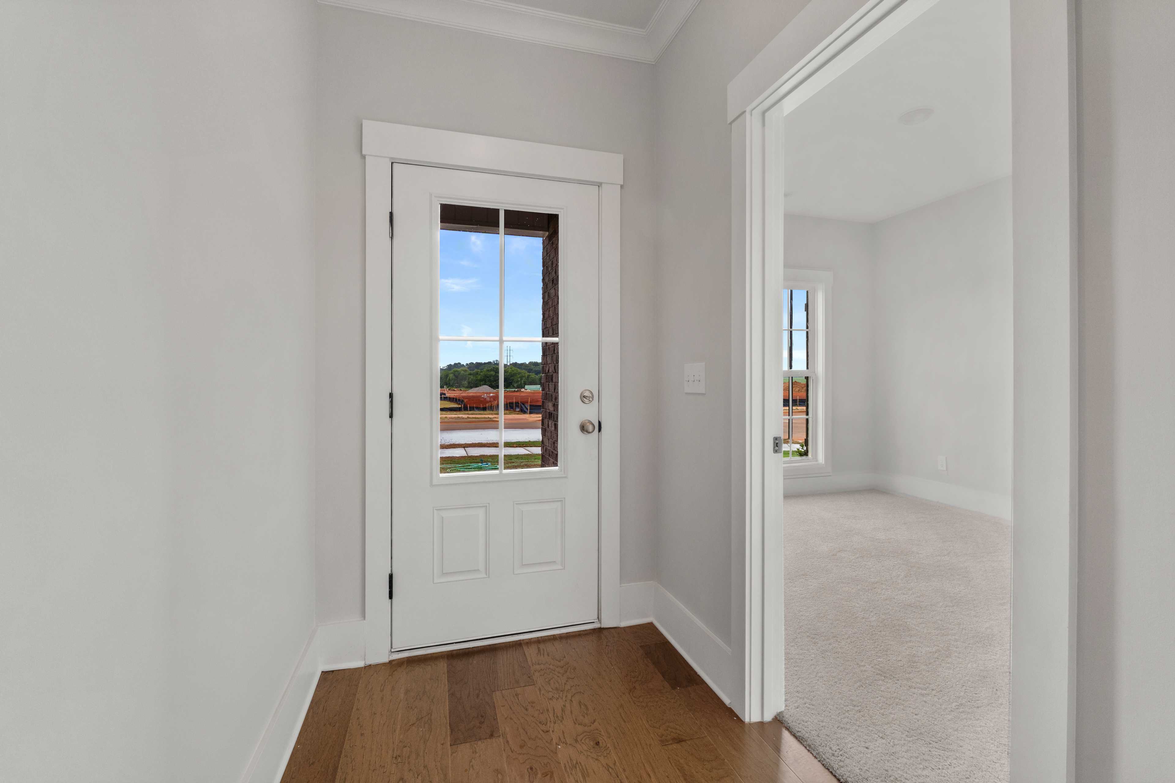 Entryway door with wooded outdoor view at The Villas at Barnett's Crossing in Madison, Alabama, hardwood floors and white trim