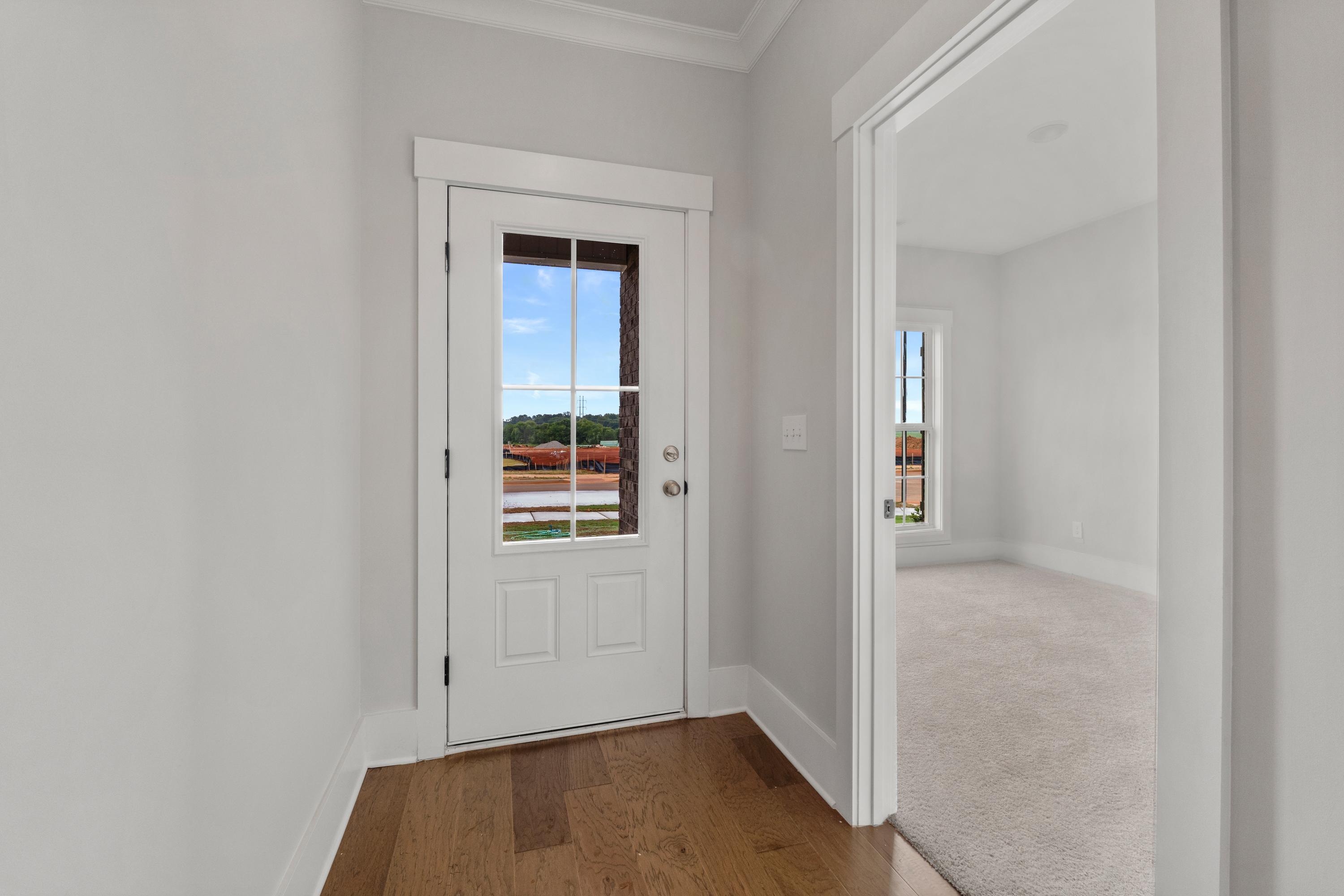 Entryway door with wooded outdoor view at The Villas at Barnett's Crossing in Madison, Alabama, hardwood floors and white trim