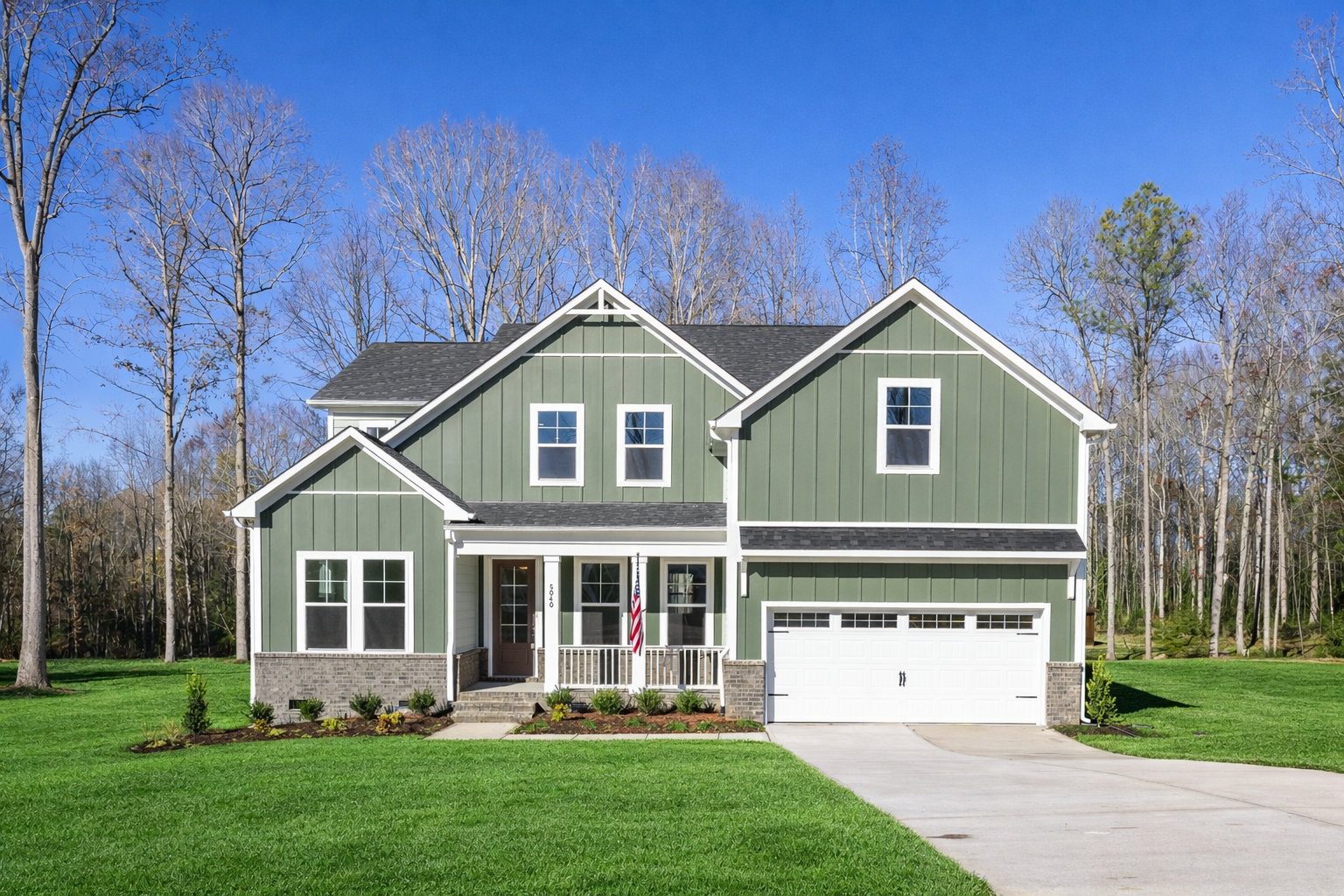 Farmhouse-style green home exterior in Rockport, Wake Forest NC with covered porch, two-car garage, and tree-lined yard by Davidson Homes