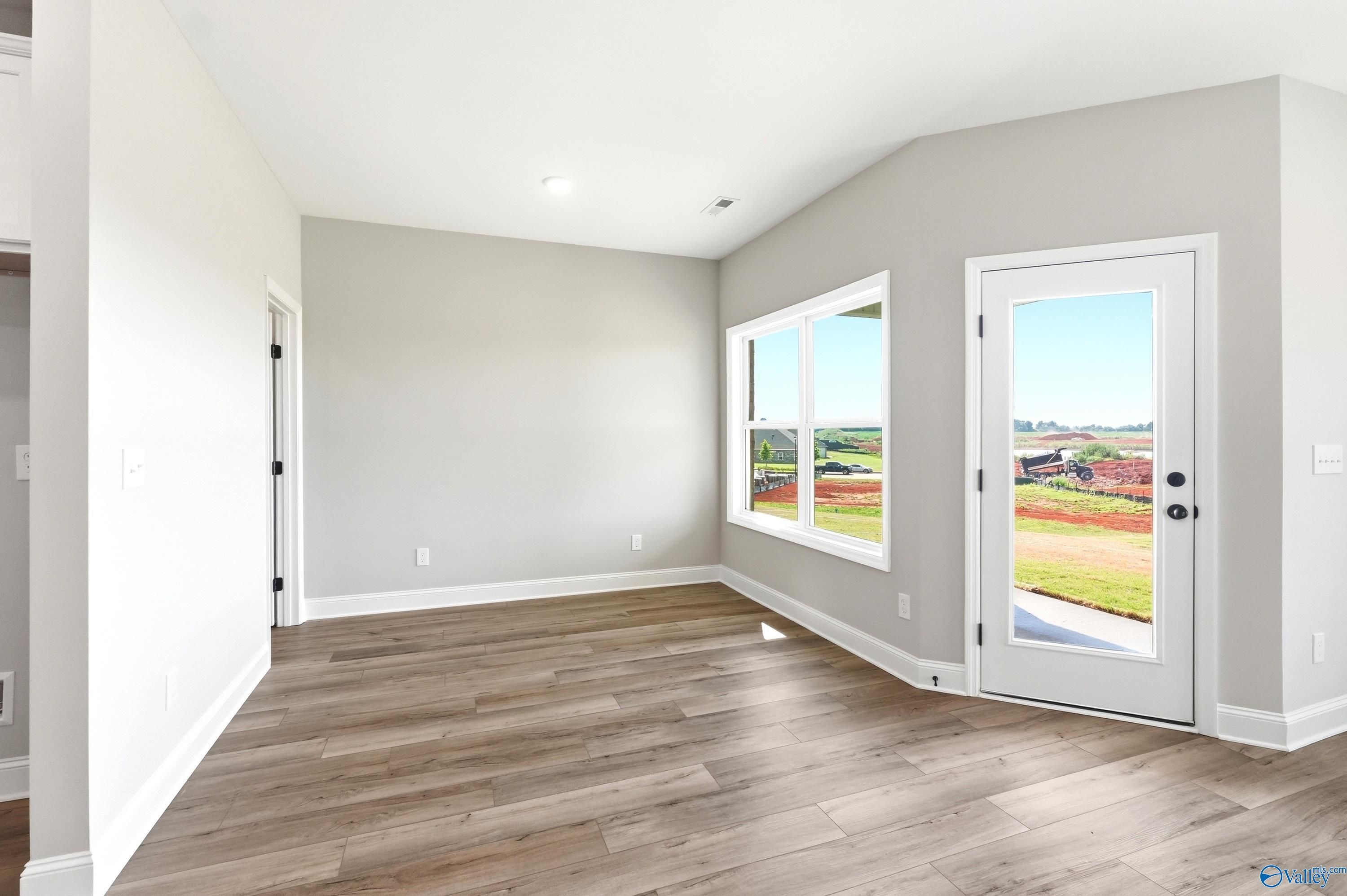 Bright, open-concept living area with wood-style flooring in The Daphne D floor plan at Creekside, Harvest, Alabama.