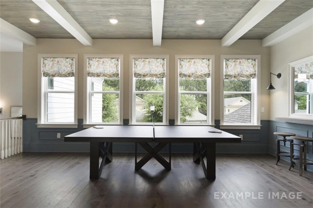 Spacious game room featuring ping pong table, hardwood floors, beamed ceiling, and large windows in Davidson Homes The Seaside A, Woodstock, GA