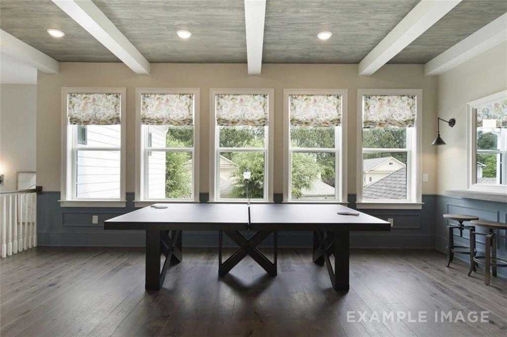 Spacious game room featuring ping pong table, hardwood floors, beamed ceiling, and large windows in Davidson Homes The Seaside A, Woodstock, GA