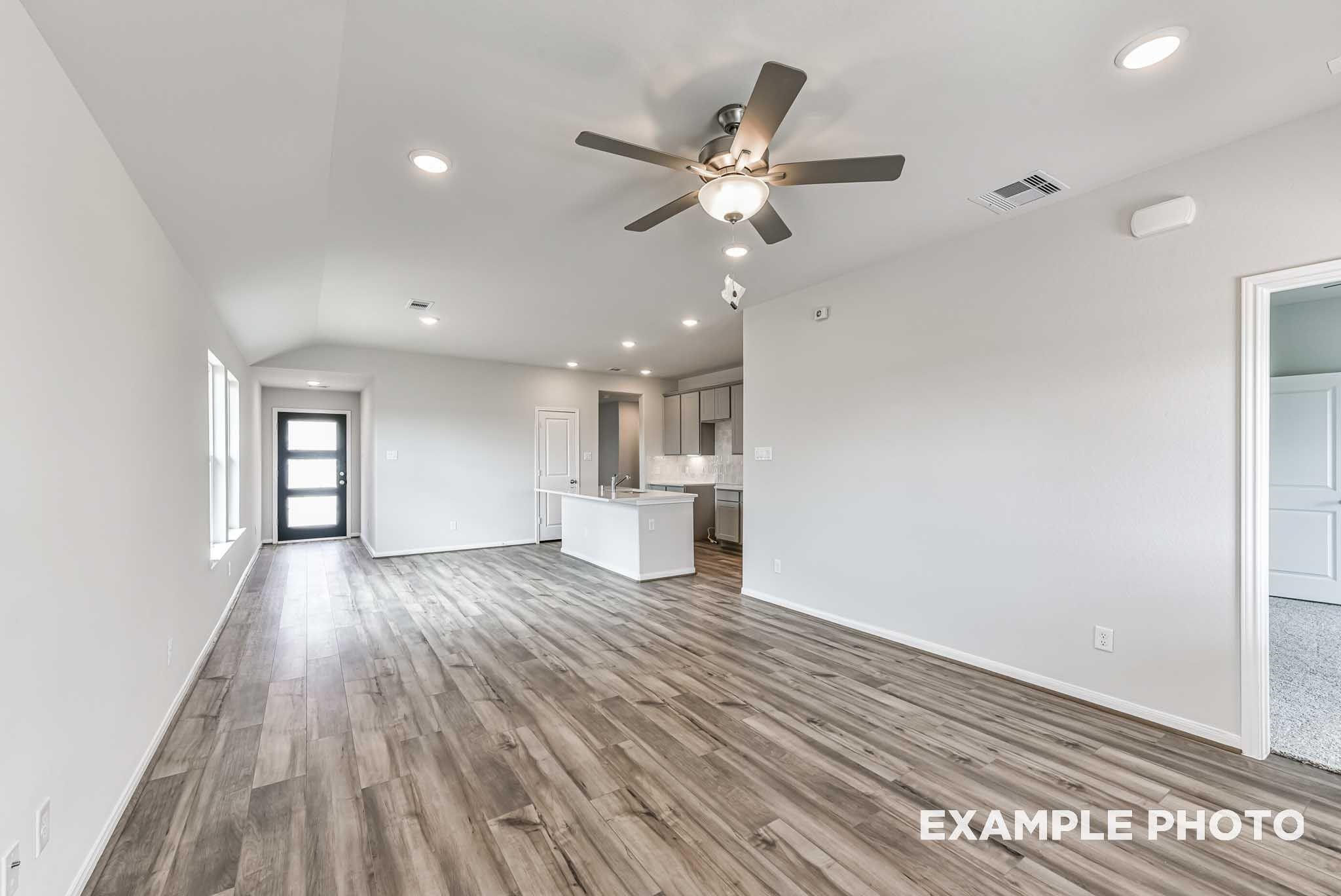 Open-concept living room with vaulted ceiling, ceiling fan, and wood-look flooring in The Costa A floor plan at River Ranch Meadows, Dayton, TX