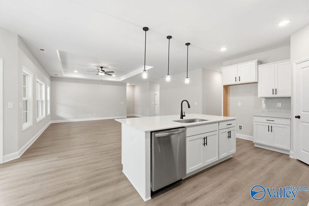 Modern open-concept kitchen with white shaker cabinets, quartz island, pendant lights, and hardwood floors in Davidson Homes The Rockford B, Hartselle, Alabama