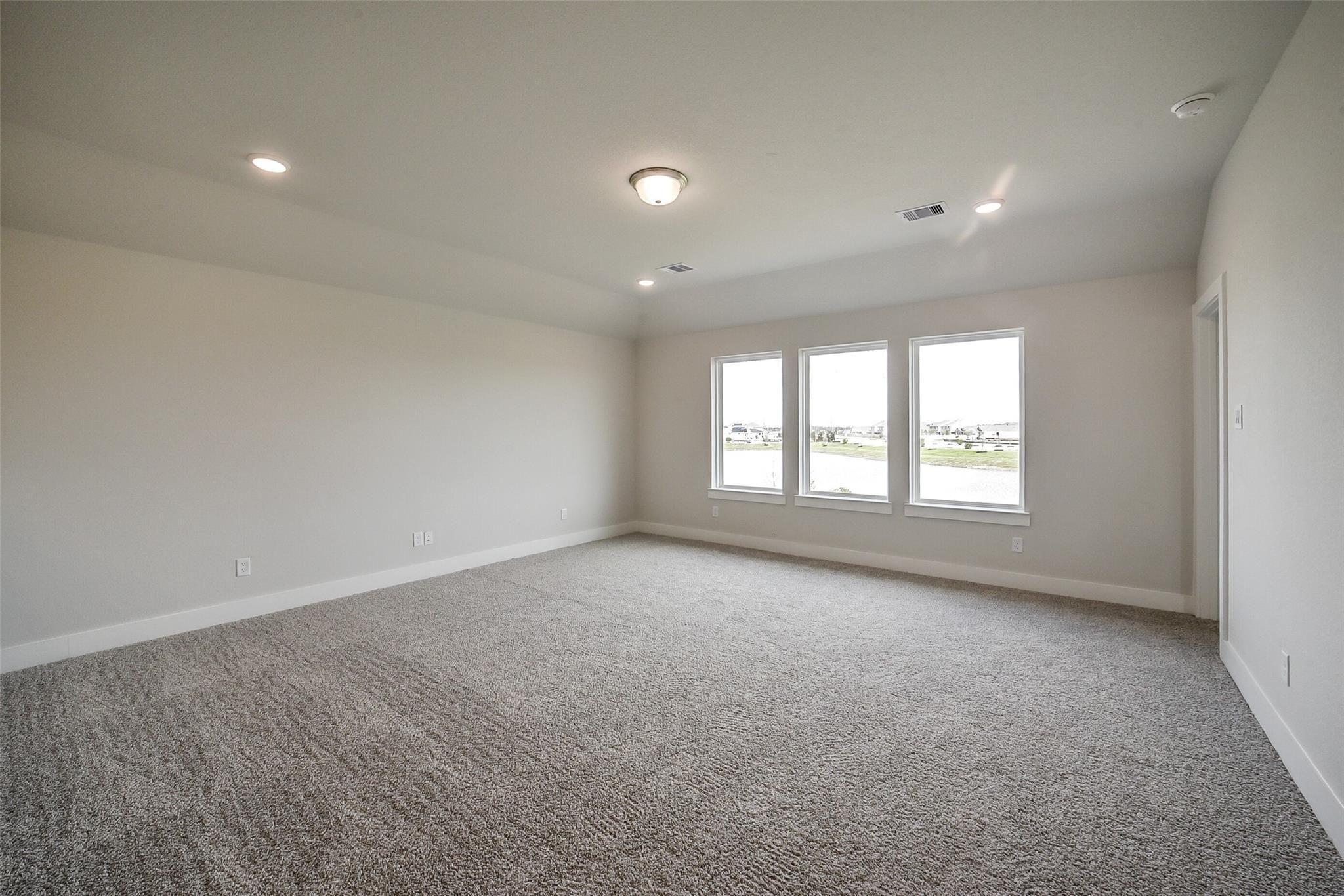 Spacious carpeted bedroom with large windows and recessed lighting in Davidson Homes The Philip B, Rosharon, Texas