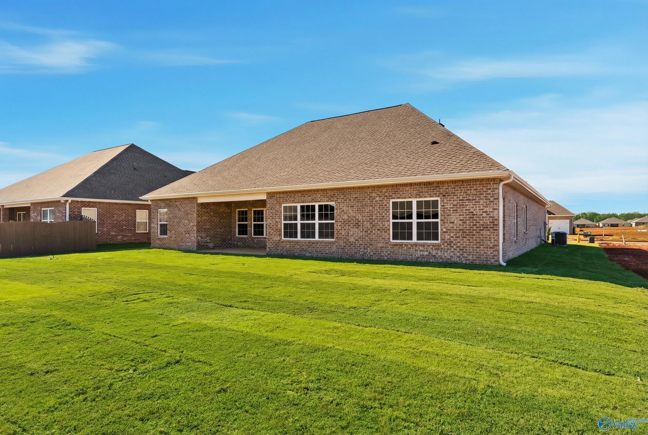 Brick single-story home with covered patio, large windows, and lush green lawn in Briercreek, Meridianville, Alabama