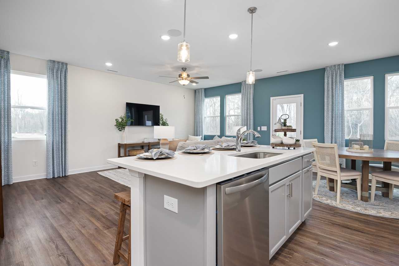 Open-concept kitchen and dining area at Gregory Village Townhomes in Lillington NC with quartz island, stainless appliances, and hardwood floors