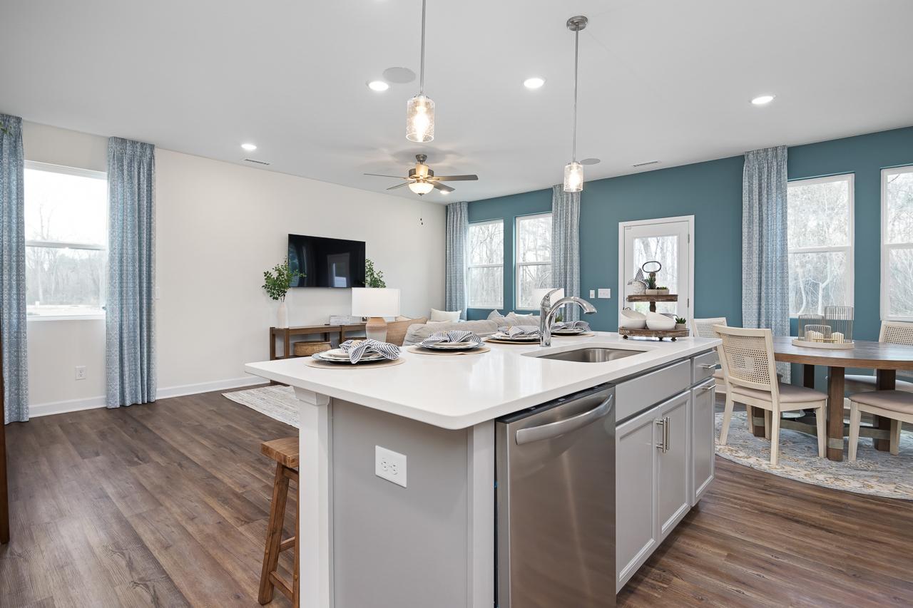 Open-concept kitchen and dining area at Gregory Village Townhomes in Lillington NC with quartz island, stainless appliances, and hardwood floors