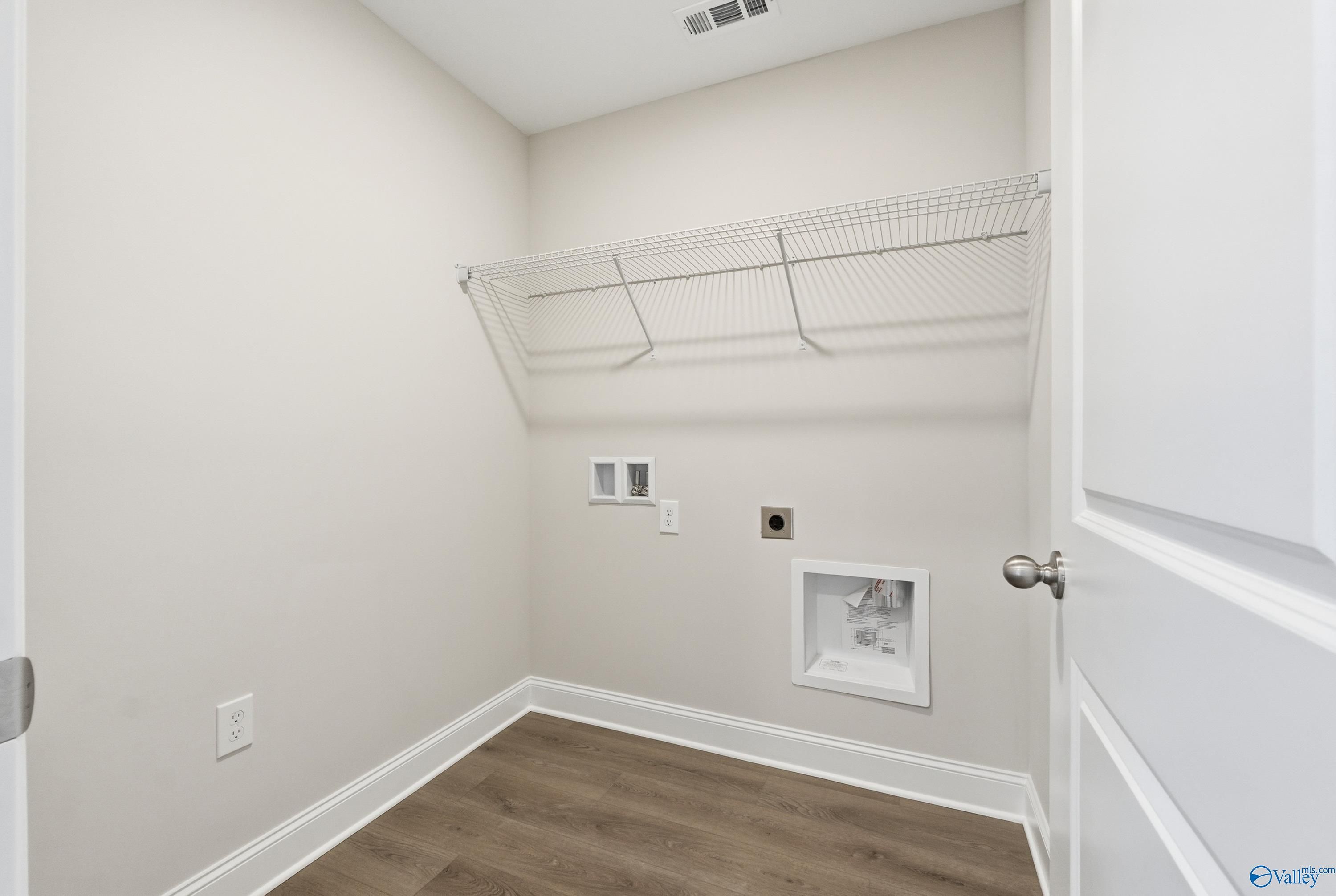 Spacious laundry room with wire shelving, washer dryer hookups, and hardwood floors in Davidson Homes The Franklin, New Market Alabama