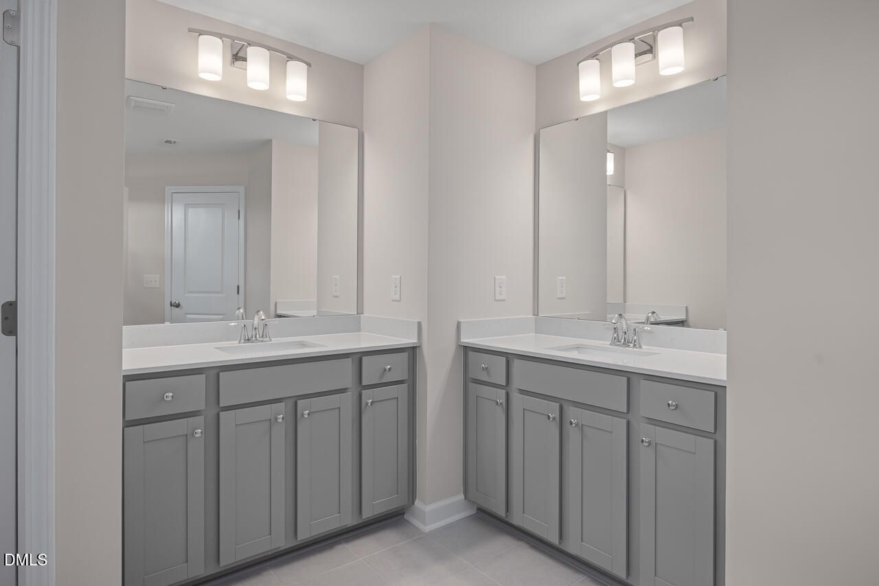 Double vanity bathroom with gray cabinets and white countertops in Davidson Homes The Graham plan, Springvale, Fuquay-Varina.
