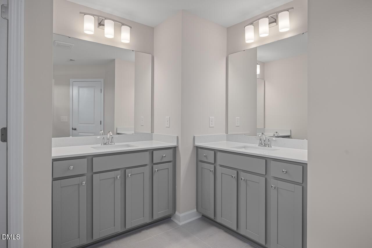 Double vanity bathroom with gray cabinets and white countertops in Davidson Homes The Graham plan, Springvale, Fuquay-Varina.