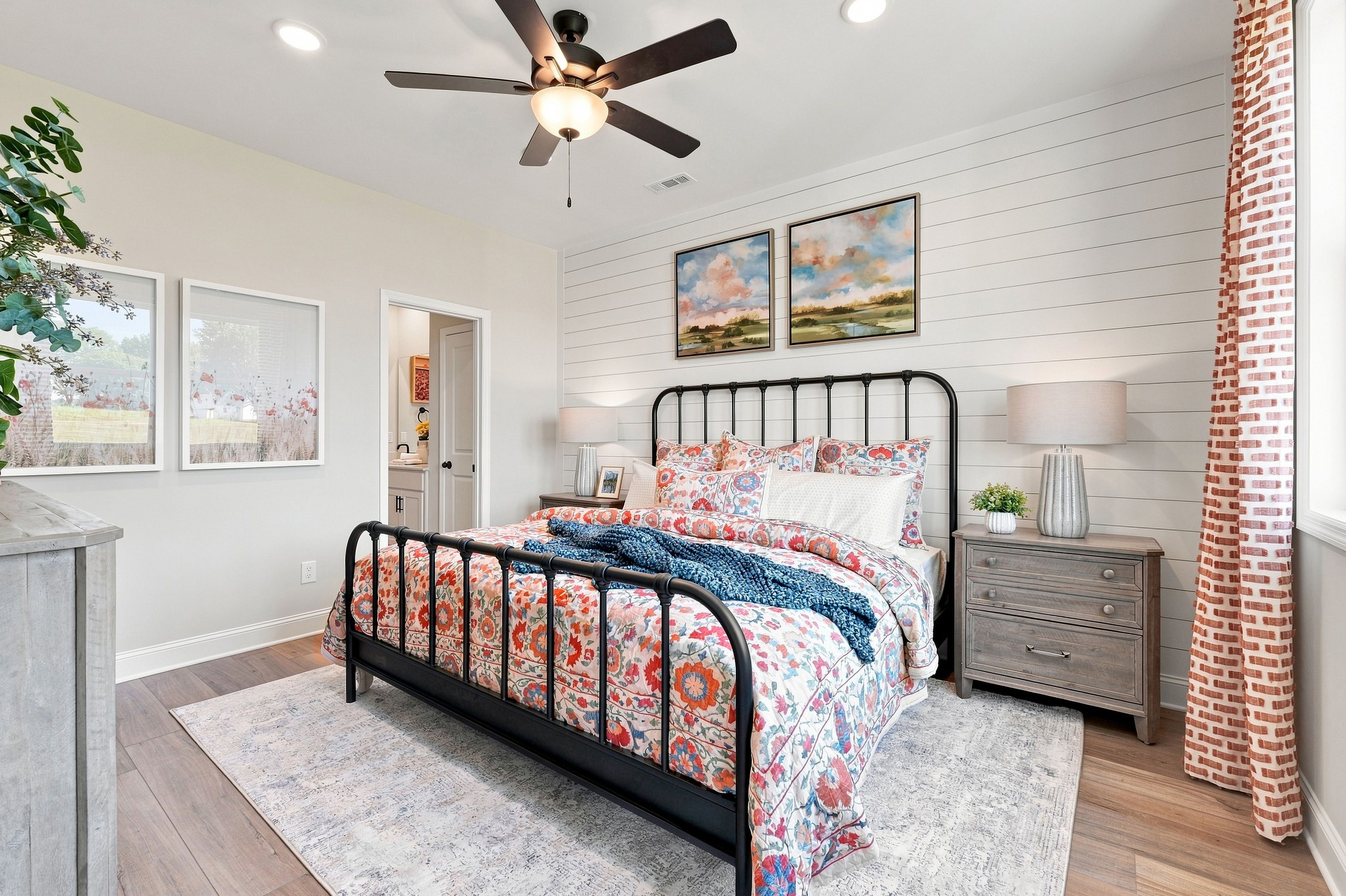 Primary bedroom at Bailey Park in Fayetteville, TN by Davidson Homes featuring black metal bed, shiplap accent wall, and ceiling fan