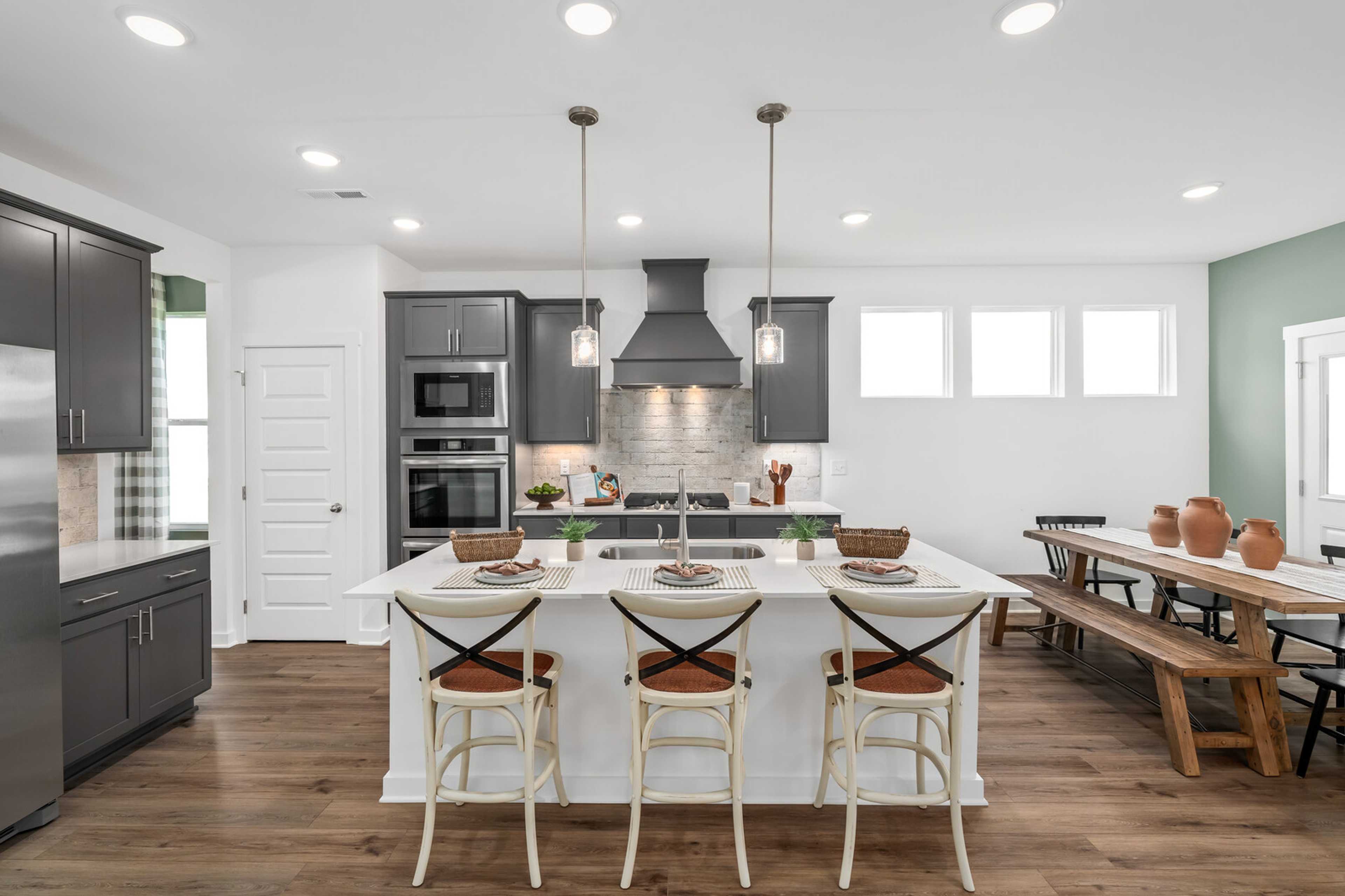 Spacious modern kitchen at Calista Farms in White House Tennessee with white island, dark cabinets and hardwood floors