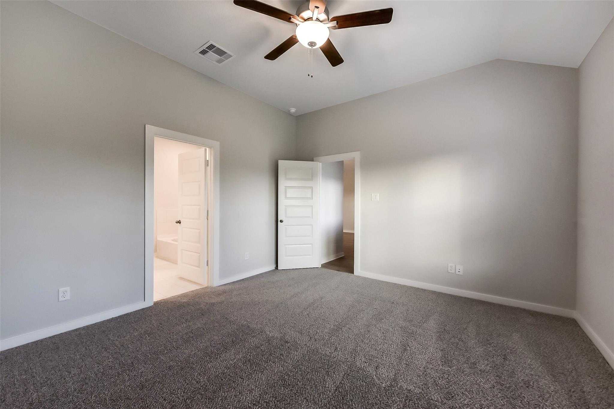 Cozy secondary bedroom featuring gray carpet, ceiling fan, and open door to attached bath in Davidson Homes The Laguna B, Katy TX
