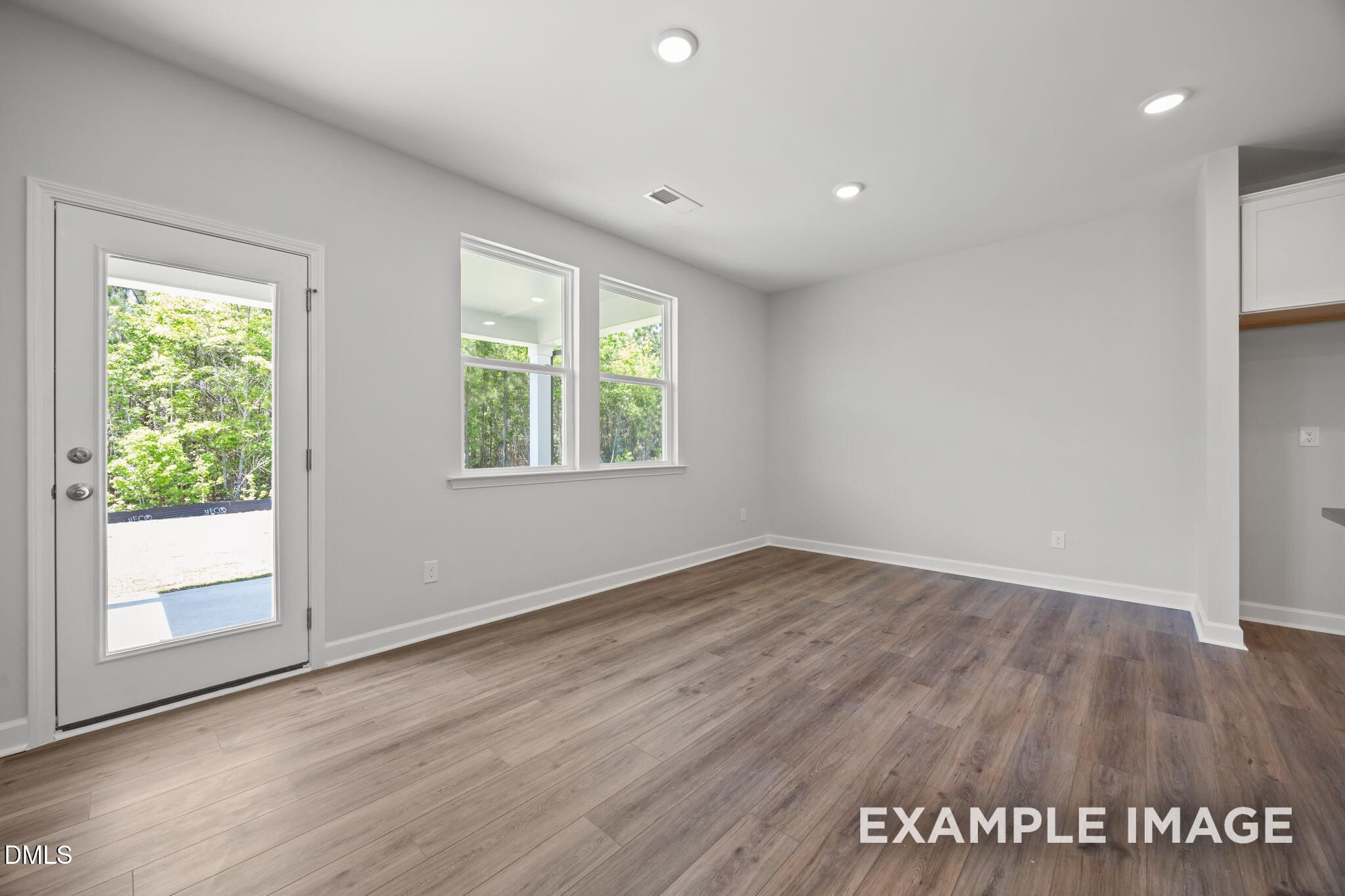 Bright open-concept dining area with luxury vinyl plank flooring and glass back door in Davidson Homes The Beech, Wendell NC