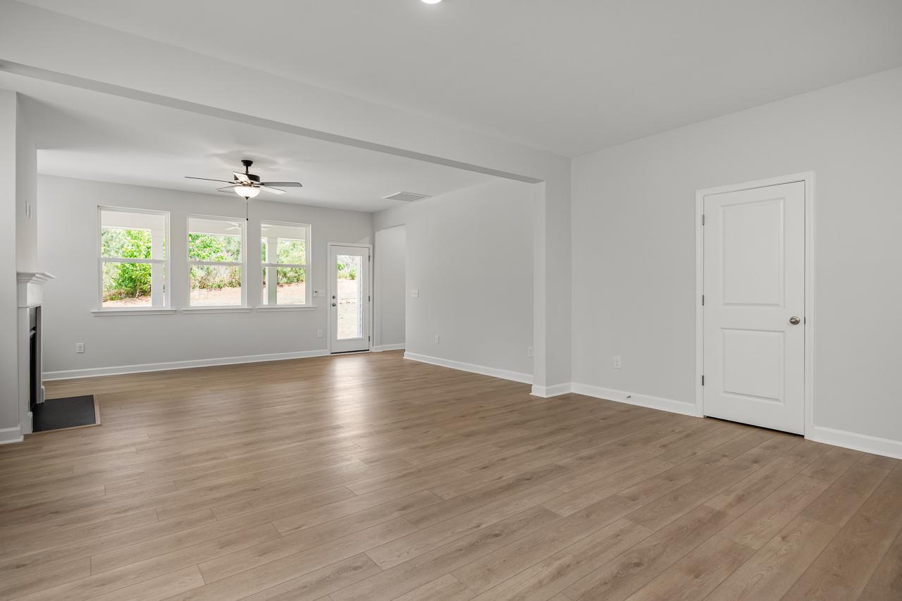 Spacious open-concept living area in The Birch II featuring light wood flooring, fireplace, and natural lighting.