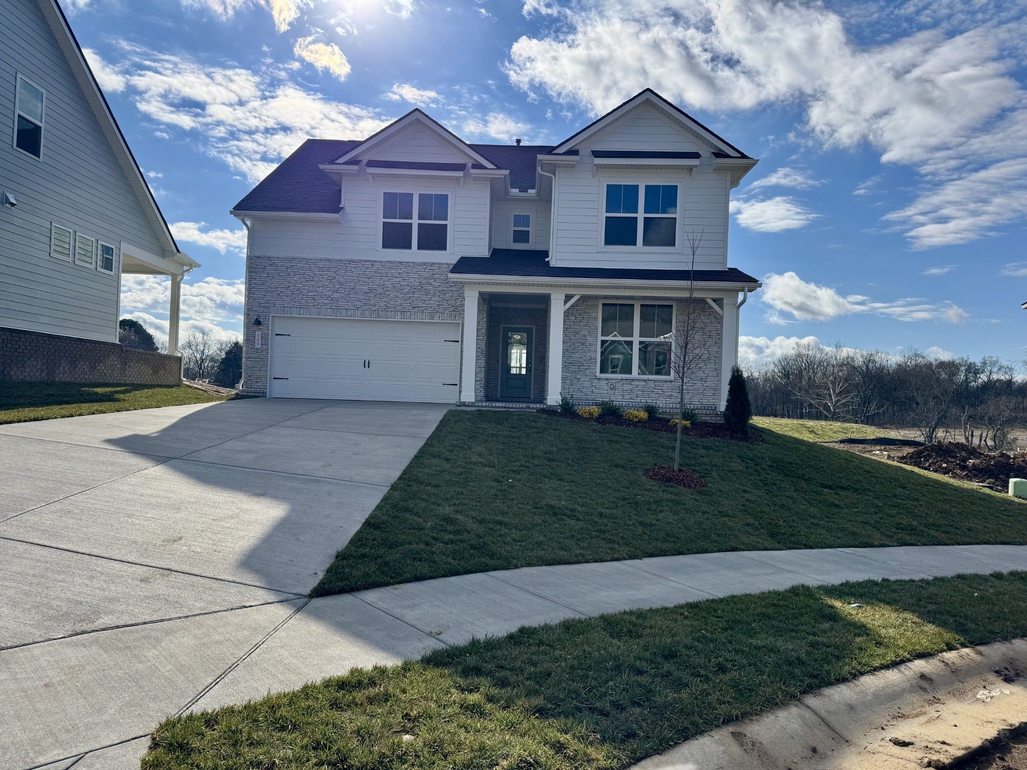 Two-story white Ridgeport home with 2-car garage, covered porch, and landscaped yard in Woods Crossing, Gallatin, Tennessee