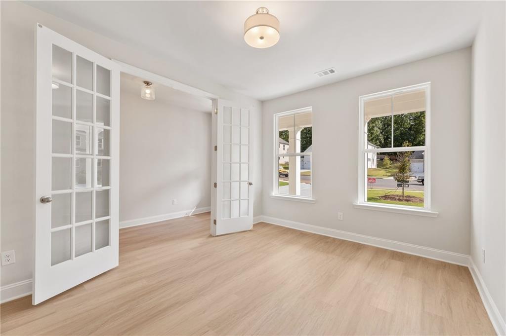 Bright interior with open white French doors, oak hardwood floors, and large windows in Davidson Homes The Hampton C, Buford, GA