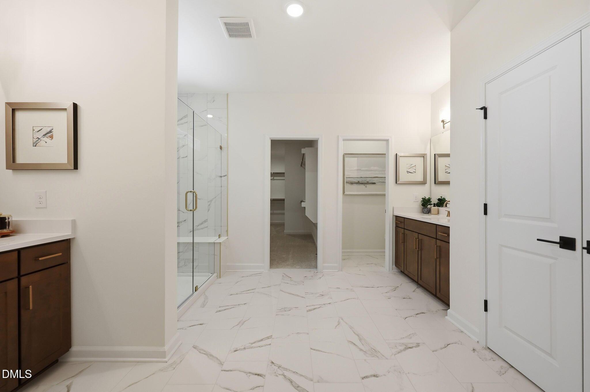 Modern primary bathroom with marble-style tile, glass shower, and walk-in closet in The Aspen B at Wendell Ridge.