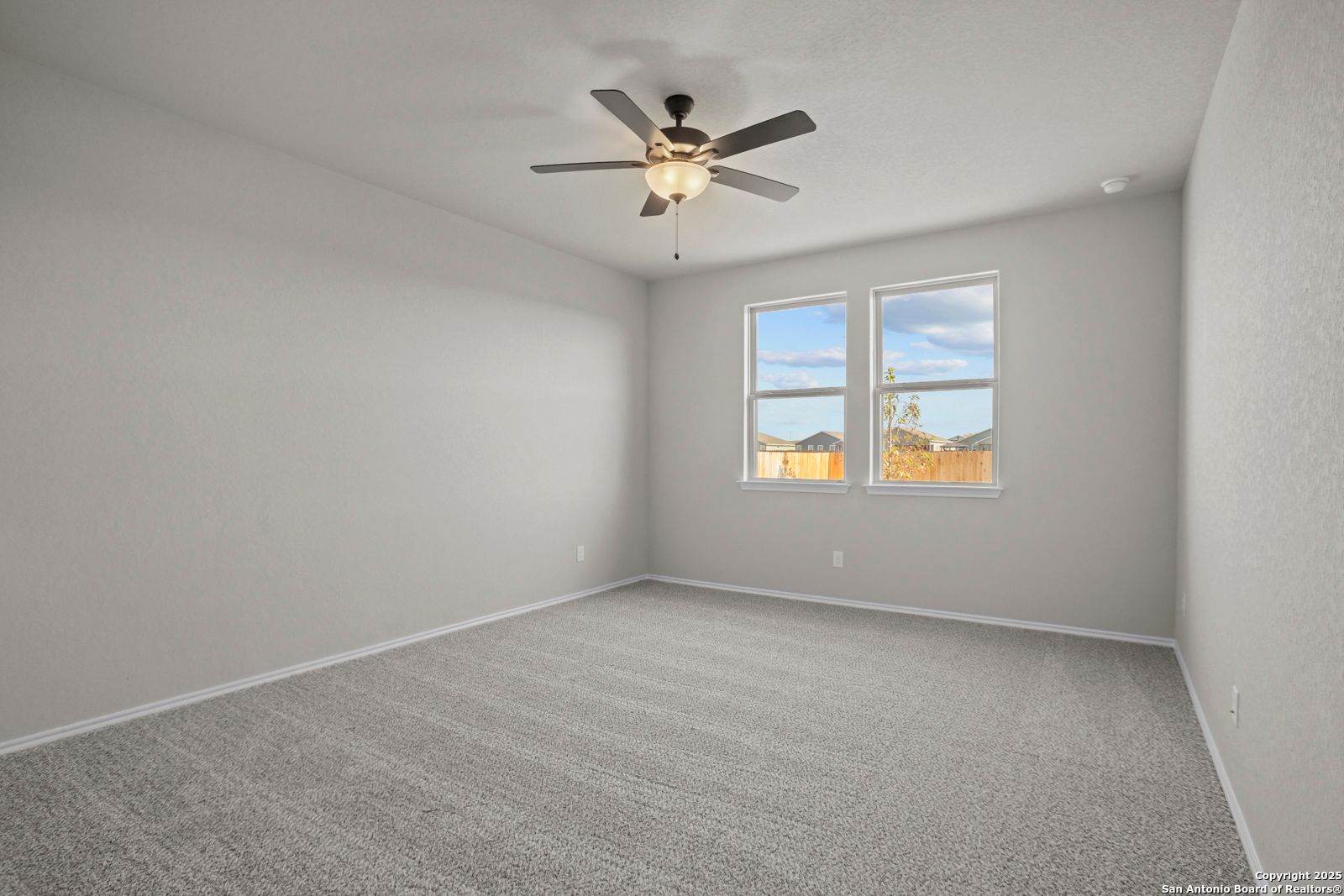 Bright secondary bedroom with gray walls, beige carpet, ceiling fan, and large windows in The Daphne H, Seguin, Texas