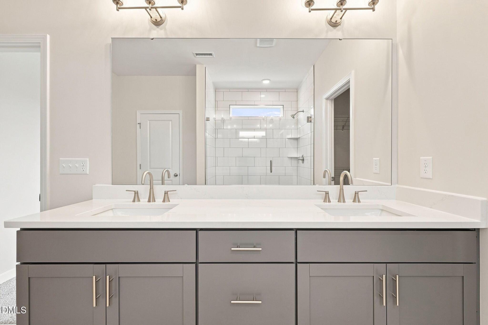 Double vanity with quartz countertop and gray cabinets in The Magnolia B floor plan at Retreat at North Main, Lillington, NC.