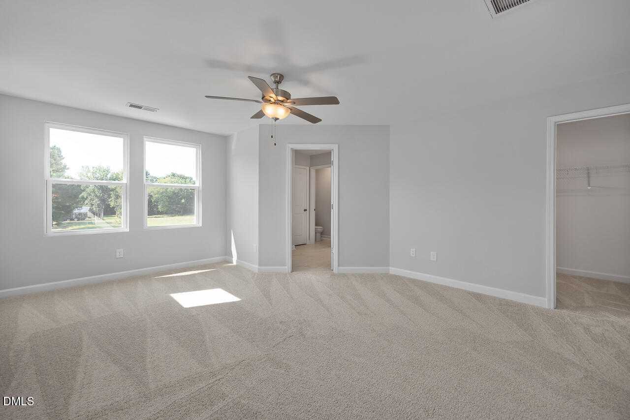 Bright master bedroom with ceiling fan, large sunny windows, attached bath, and closet in Davidson Homes The Graham, Fuquay-Varina, NC