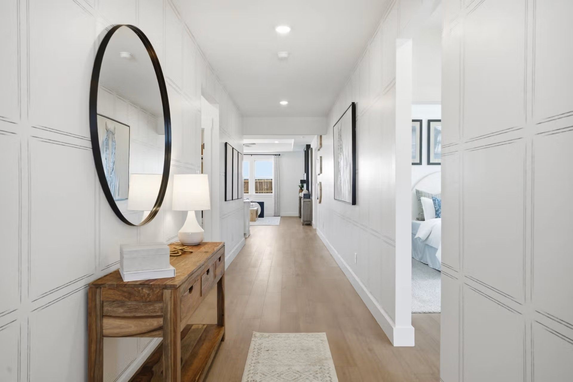 Bright hallway with wood console table and oval mirror in The Laurel O floor plan at Mercer Meadows, Royse City, Texas.