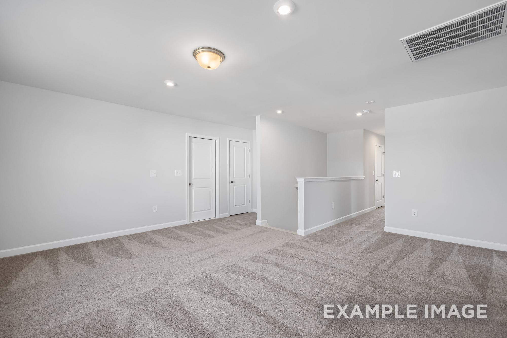 Spacious upstairs hallway in The Cypress B II by Davidson Homes, featuring gray carpet, white walls, bedroom doors, and railing